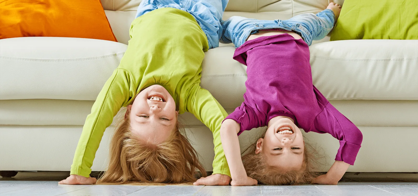 Two happy children playing upside down on a couch
